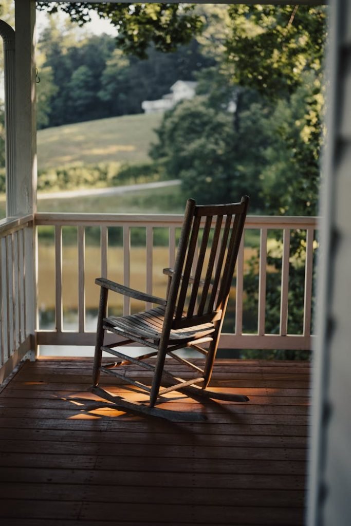 old-wooden-rocking-chair-on-the-porch-of-a-country-house-20778163 A serene countryside view from a porch with a wooden rocking chair, ideal for relaxation.